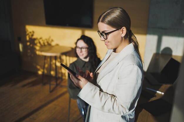 Lavoro d'ufficio attraente giovane manager femminile che lavora in ufficio in piedi in un'area di lavoro luminosa utilizzando un moderno computer portatile ragazza che ha una videochiamata tramite laptop