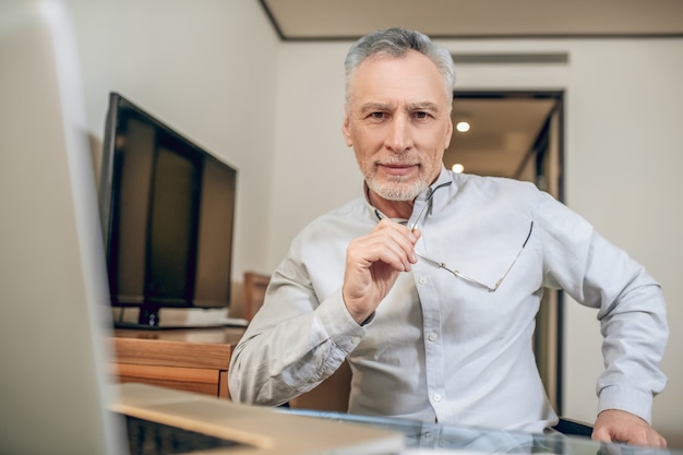 Lavoro da casa. Uomo dai capelli grigi che lavora da casa e sembra occupato