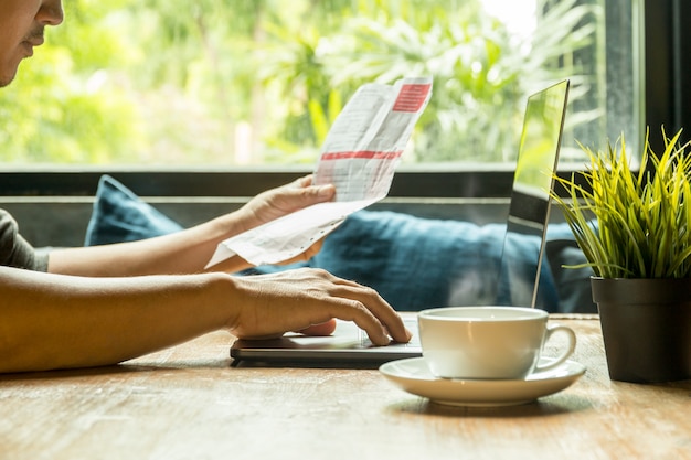 Lavoro dell&#39;uomo d&#39;affari sul computer portatile che controlla fattura con caffè sulla tavola di legno