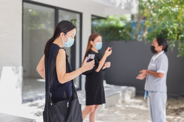 Lavoro di squadra della donna di affari nella mascherina medica che lavora al telefono cellulare.