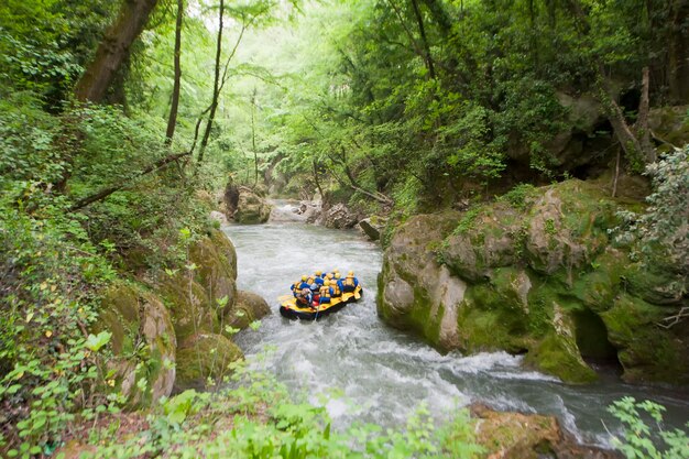 Lavoro di squadra di persone che fanno rafting su un torrente in barca gialla