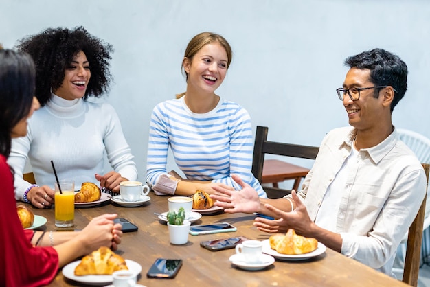 Lavoro di squadra in un momento di relax gruppo di giovani millennial che fanno colazione croissant caffè e cappuccino sul tavolo di un bar