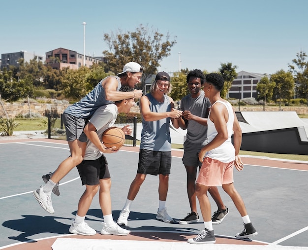 Lavoro di squadra sportivo e amici con l'uomo di pallacanestro in campo per il supporto e l'energia del vincitore Fitness estivo ed esercizio fisico con allenamento del giocatore di basket e risultati per la salute e l'allenamento dei giochi