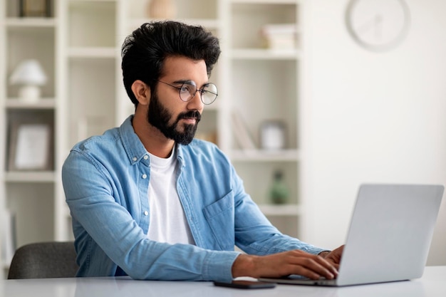 Lavoro freelance bel giovane indiano che lavora al computer in ufficio a casa