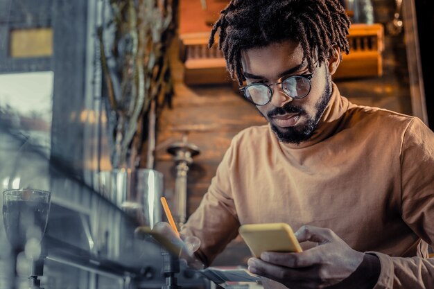 Lavoro online. Bello maschio barbuto chinando la testa mentre fissa lo schermo del suo gadget