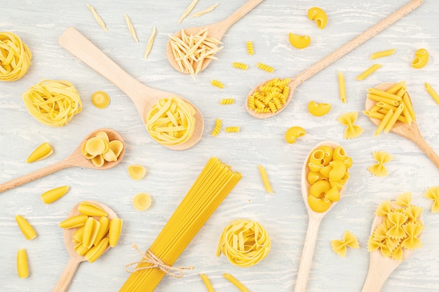 Lay piatto con diversi tipi di pasta italiana tradizionale. Penne, tagliatelle, fusilli, farfalle, spaghetti e altri. Concetto di cucina italiana tradizionale. Vista dall'alto