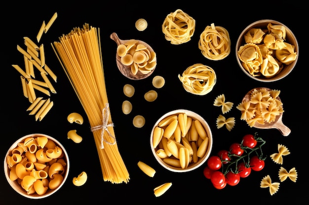 Lay piatto con diversi tipi di pasta italiana tradizionale. Penne, tagliatelle, fusilli, farfalle, spaghetti e altri. Concetto di cucina italiana tradizionale. Vista dall'alto