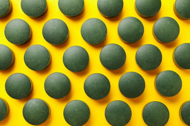 Lay piatto con spirulina pillole su sfondo giallo, vista dall'alto