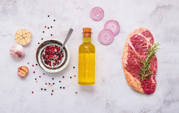 Lay piatto di bistecca di manzo crudo fresco con rosmarino e spezie su sfondo bianco squallido cemento vista dall'alto