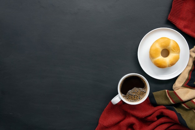 Lay piatto di caffè caldo, maglione e ciambelle