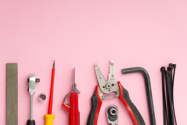 Lay piatto di un set di strumenti per la riparazione domestica su uno sfondo rosa