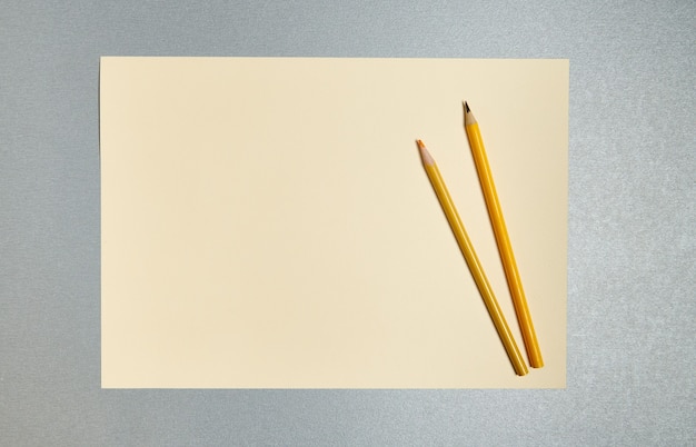 Lay piatto. Matite di legno su un foglio di carta gialla. Vista dall'alto di strumenti gialli su sfondo grigio