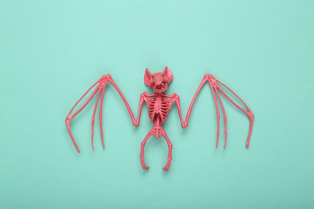 Layout creativo di halloween Scheletro di pipistrello rosa su sfondo blu menta Minimalismo Concept art Idea fresca Posa piatta Vista dall'alto