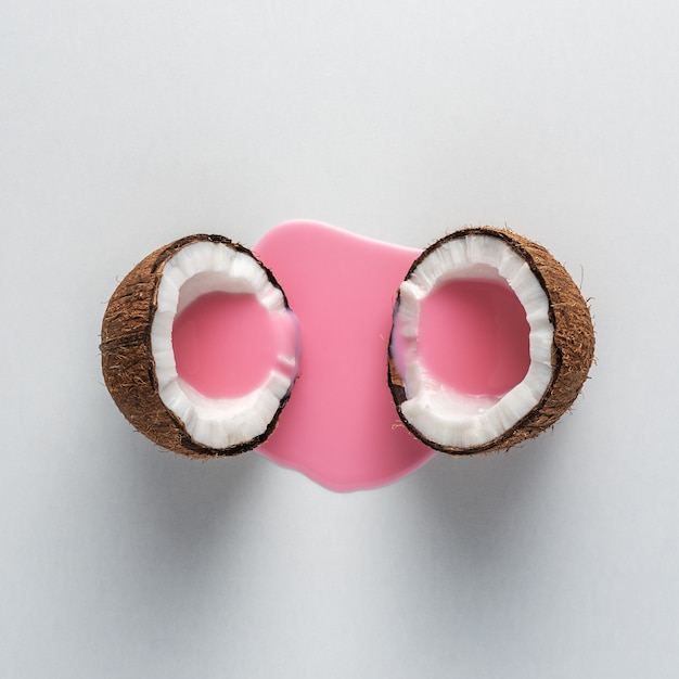 Layout creativo fatto di cocco a metà con versamento di latte rosa