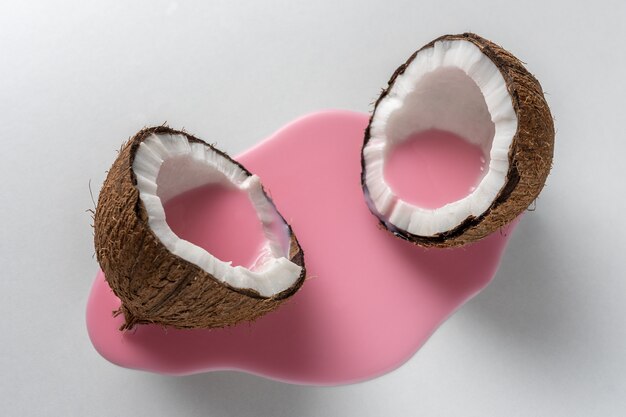 Layout creativo fatto di cocco a metà con versamento di latte rosa.