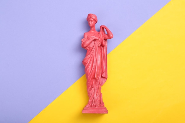 Layout creativo Statua della dea greca antica rosa su sfondo giallo viola Vista dall'alto piatta