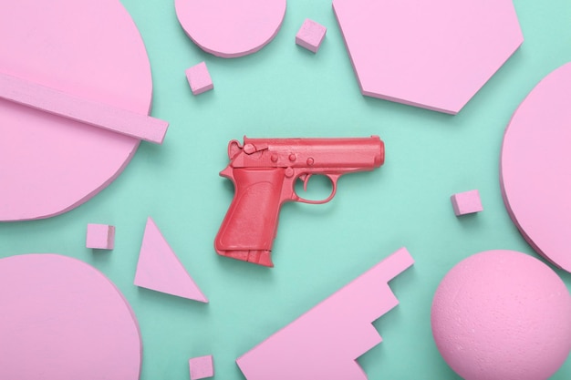 Layout minimale creativo Pistola rosa con diverse forme geometriche su sfondo blu menta Minimalismo Concept art Posa piatta Vista dall'alto