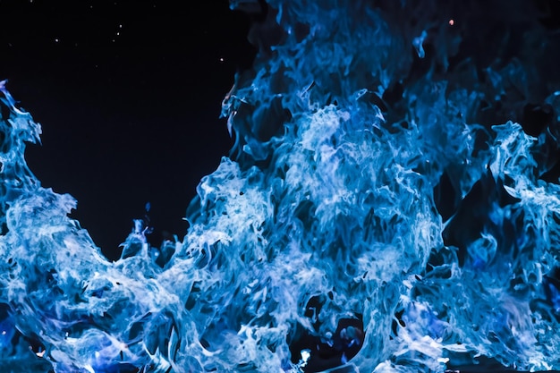 Le affascinanti fiamme blu danzavano graziosamente sullo sfondo nero come il fango.