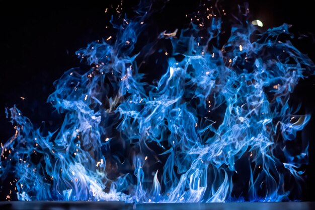 Le affascinanti fiamme blu danzavano graziosamente sullo sfondo nero come il fango.