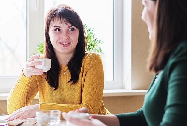 Le amiche si siedono bevendo caffè e spettegolando