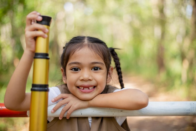 Le bambine asiatiche esplorano la natura attraverso lenti d'ingrandimento e binocoli nel parco Viaggi didattici concetti di ricerca e scoperta