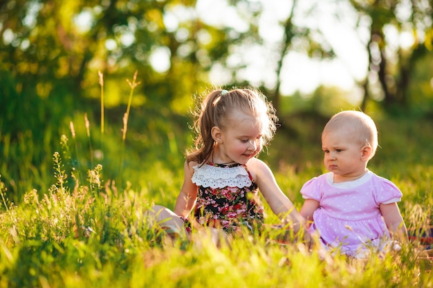 Le bambine di 1 e 3 anni sono sedute sull'erba verde