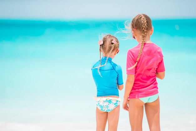 Le bambine divertenti felici si divertono molto in spiaggia tropicale giocando insieme.