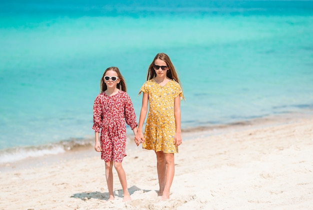 Le bambine divertenti felici si divertono molto in spiaggia tropicale giocando insieme.