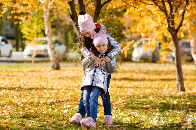Le bambine in abiti identici si divertono a passeggiare nel parco in autunno