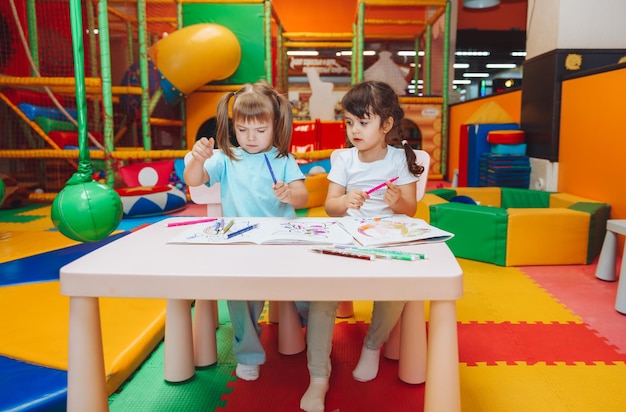Le bambine sono sedute a un tavolo e disegnano in un centro giochi per bambini la creatività dei bambini