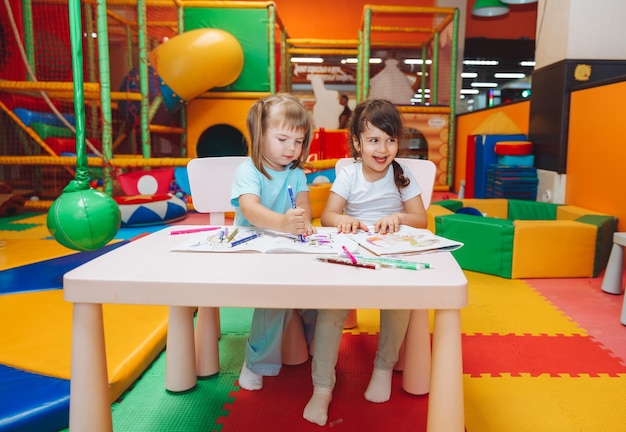 Le bambine sono sedute a un tavolo e disegnano in un centro giochi per bambini la creatività dei bambini