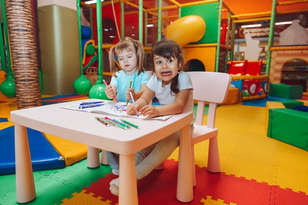 Le bambine sono sedute a un tavolo e disegnano in un centro giochi per bambini la creatività dei bambini