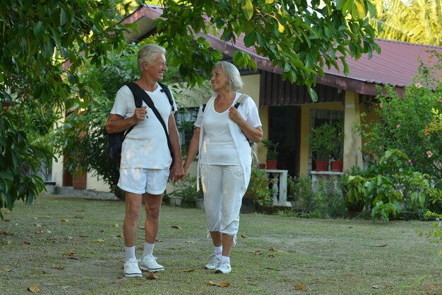 Le belle coppie anziane felici riposano alla località di soggiorno tropicale con gli zaini?