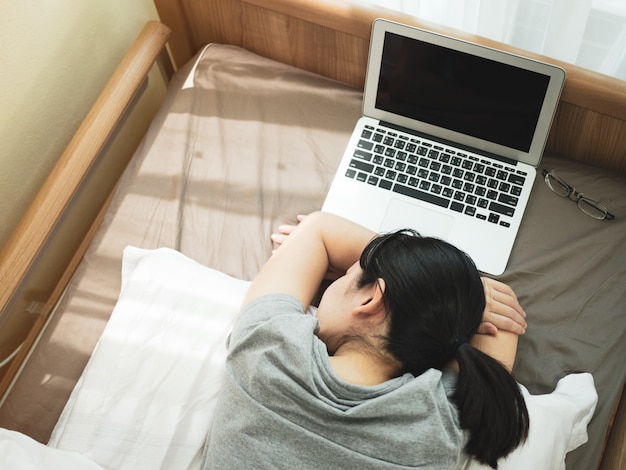 Le belle donne asiatiche lavorano a casa facendo uso del taccuino e del sonno stanco dopo l'incontro con il gruppo