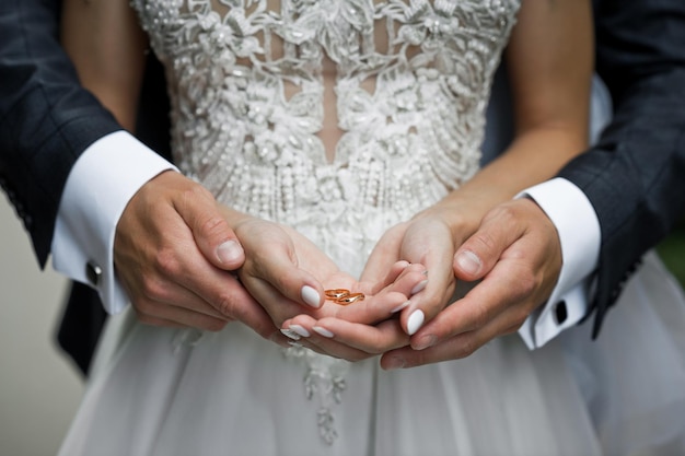 Le belle mani degli sposi novelli si abbracciano tenendo il matrimonio