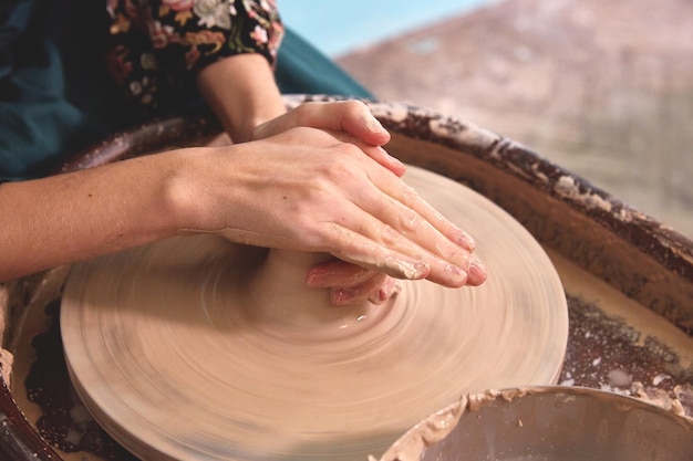 Le belle mani delle donne realizzano piatti di ceramica su un tornio da vasaio