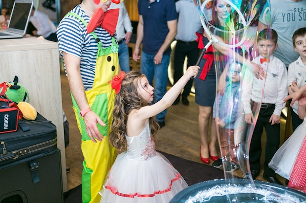 Le bolle di sapone mostrano i pagliacci alla festa dei bambini I pagliacci tengono spettacoli per eventi per bambini