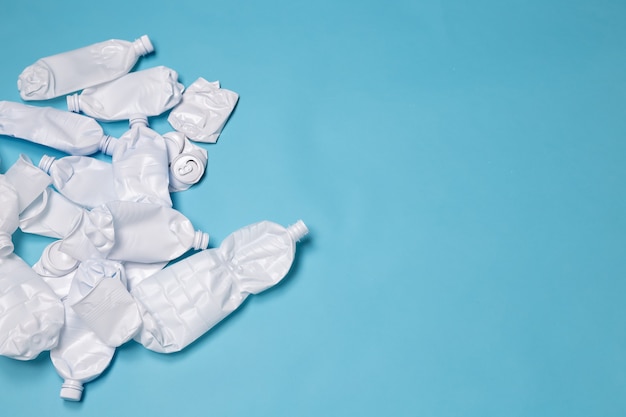 Le bottiglie di plastica della spazzatura sono su una parete blu con spazio di copia. Concetto di intasamento delle risorse naturali e lavorazione dei prodotti in plastica. .