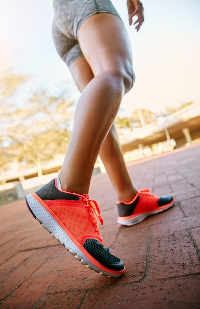 Le calzature adeguate sono importanti Inquadratura dal basso di una donna atletica irriconoscibile che va a correre in città