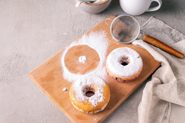 Le ciambelle in zucchero a velo giacciono su una tavola di legno