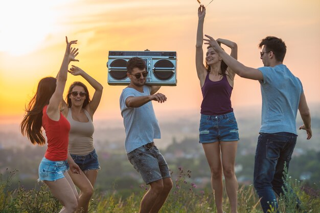 Le cinque persone che ballano sulla collina sullo sfondo del tramonto