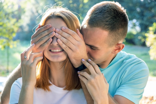 Le coppie adolescenti felici che si divertono insieme all'aperto nel sole dell'estate parcheggiano sorprendendosi con gli occhi di chiusura.