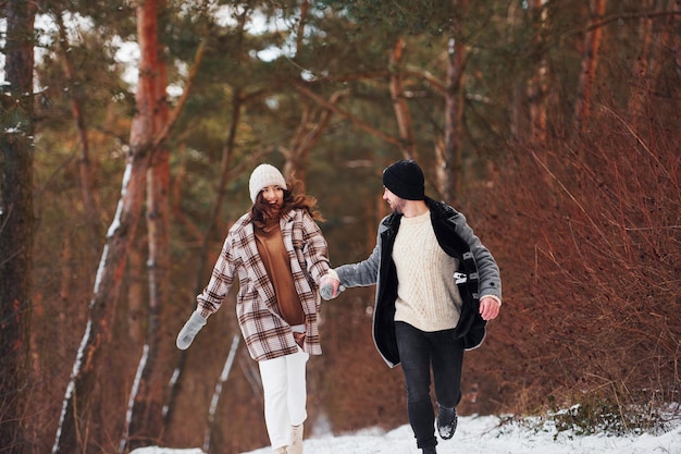 Le coppie allegre fanno una passeggiata nella foresta d'inverno durante il giorno