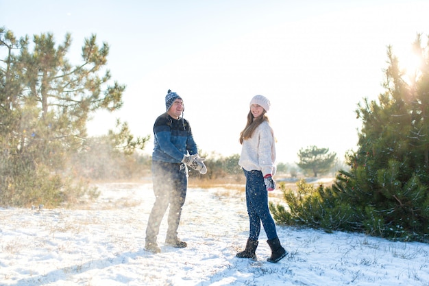 Le coppie amorose giocano a palle di neve in inverno nella foresta. Lancia l'un l'altro la neve. Ridi e divertiti