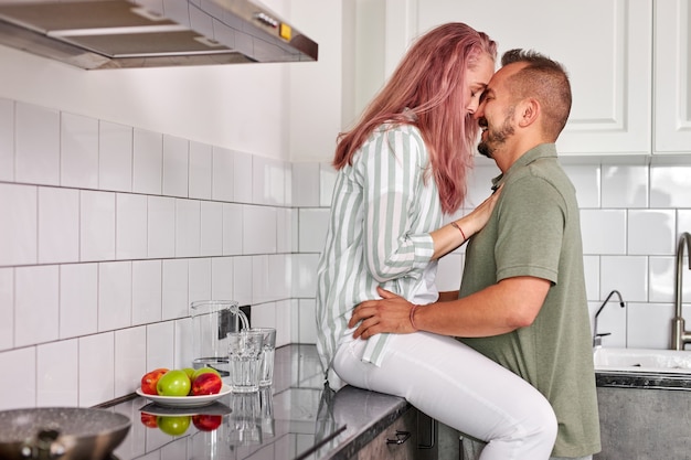 Le coppie che abbracciano in cucina, l'uomo romantico e la donna hanno tempo di relax al mattino