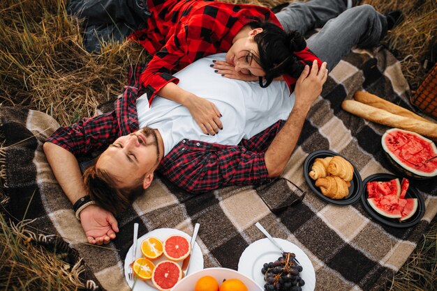 Le coppie di amore si trovano sul plaid, picnic nel campo estivo. Giunco romantico di uomo e donna