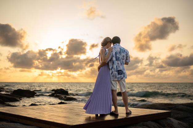 Le coppie innamorate che si abbracciano sulla spiaggia si godono il momento romantico del tramonto