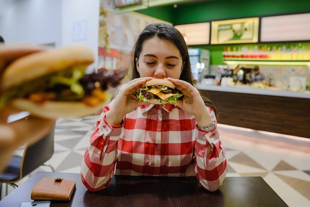 Le coppie mangiano i cheeseburger nella caffetteria