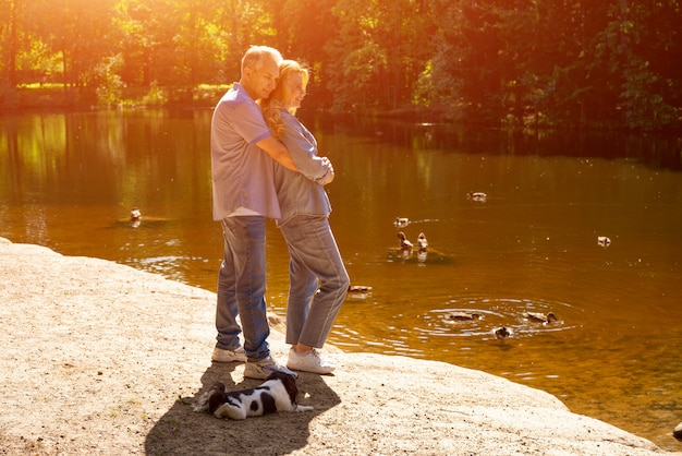Le coppie mature felici stanno in un abbraccio sul lago al sole