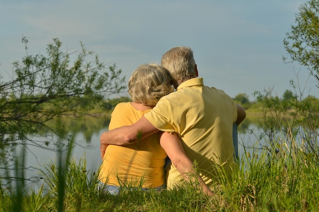 Le coppie senior felici si avvicinano al lago durante il tramonto all&#39;estate